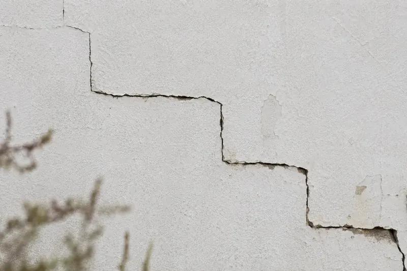 Fissure en escalier dans l'enduit d'une façade du littoral